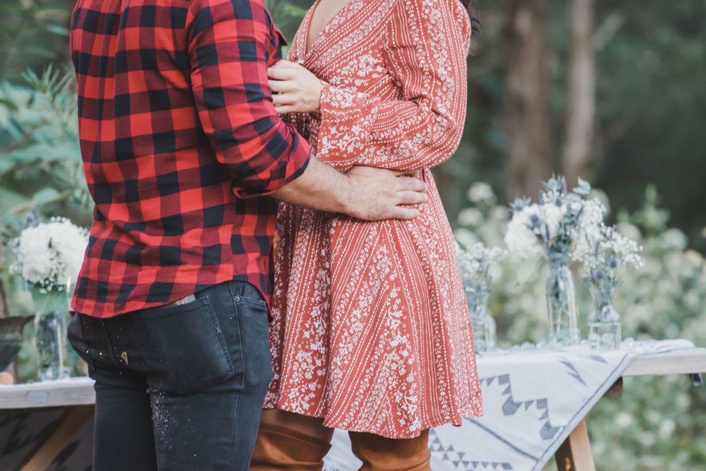 guy in red buffalo plaid shirt and woman in dress holding each others waist