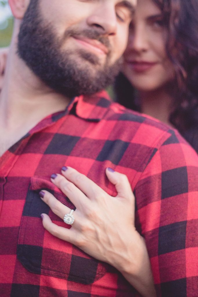 round diamond engagement ring with halo on guy in red buffalo plaid