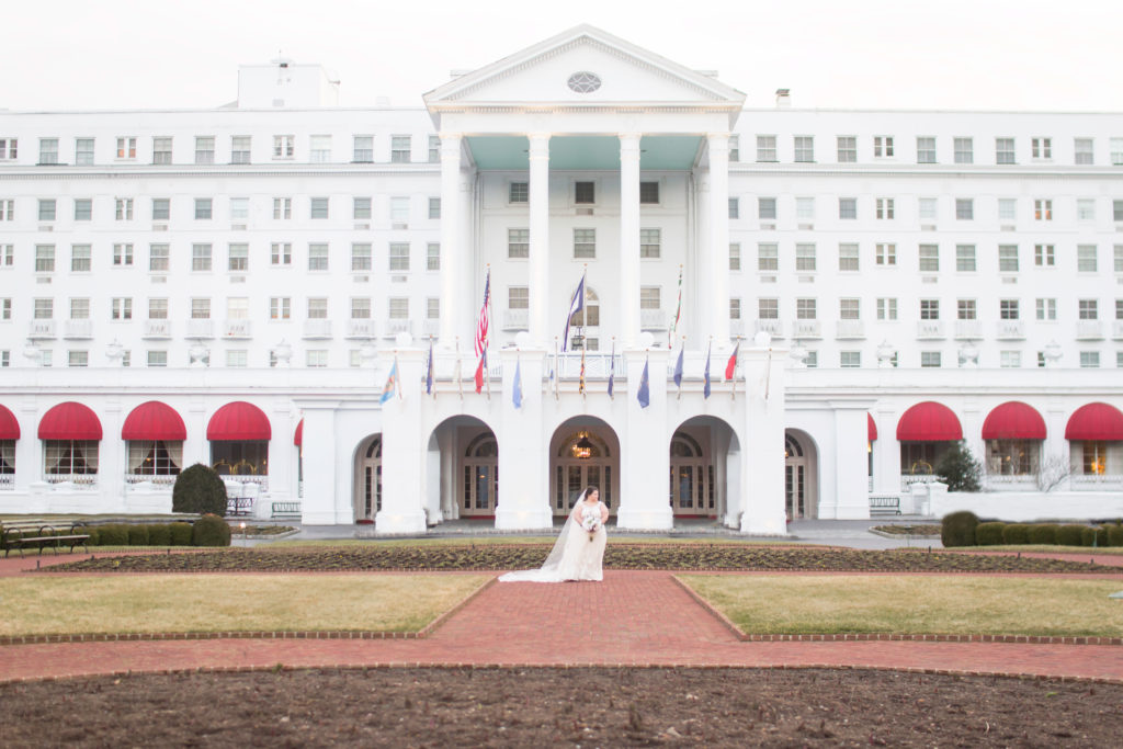 bride standing in front of huge white old greenrbier resort hotel