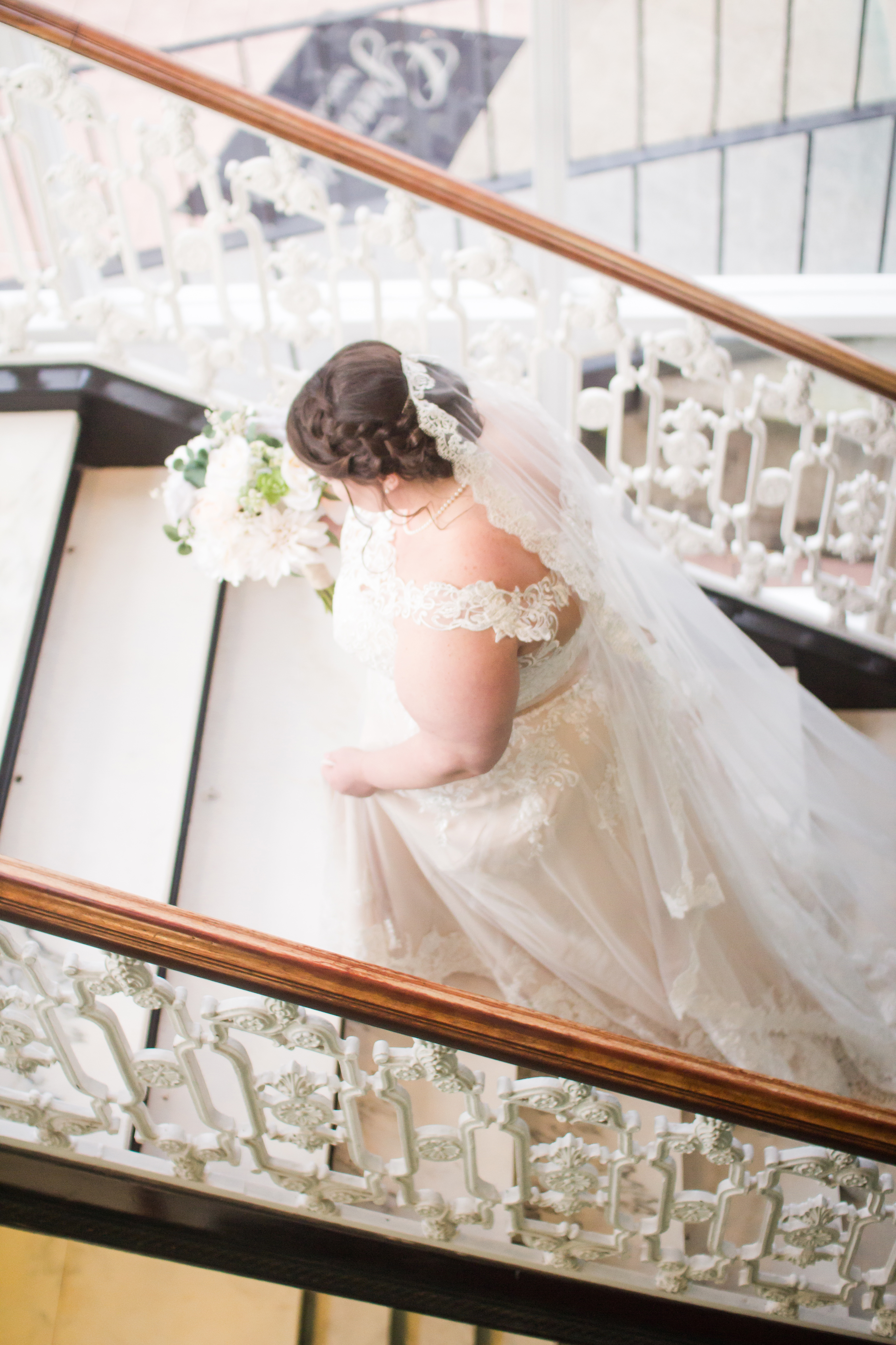 bride wearing veil going up white marble stairs