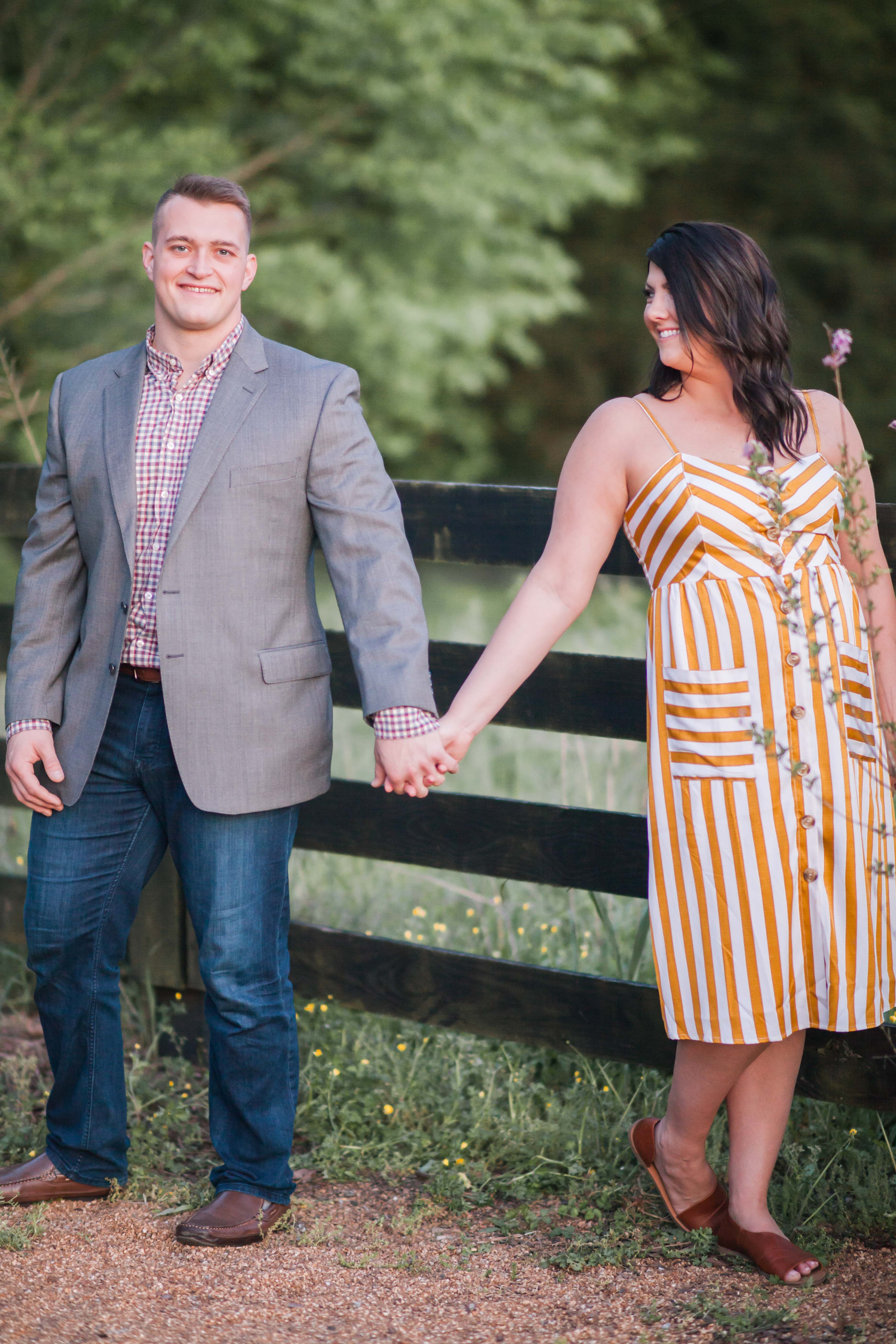 man in jeans and gray jacket holding hands with woman in mustard yellow stripe dress