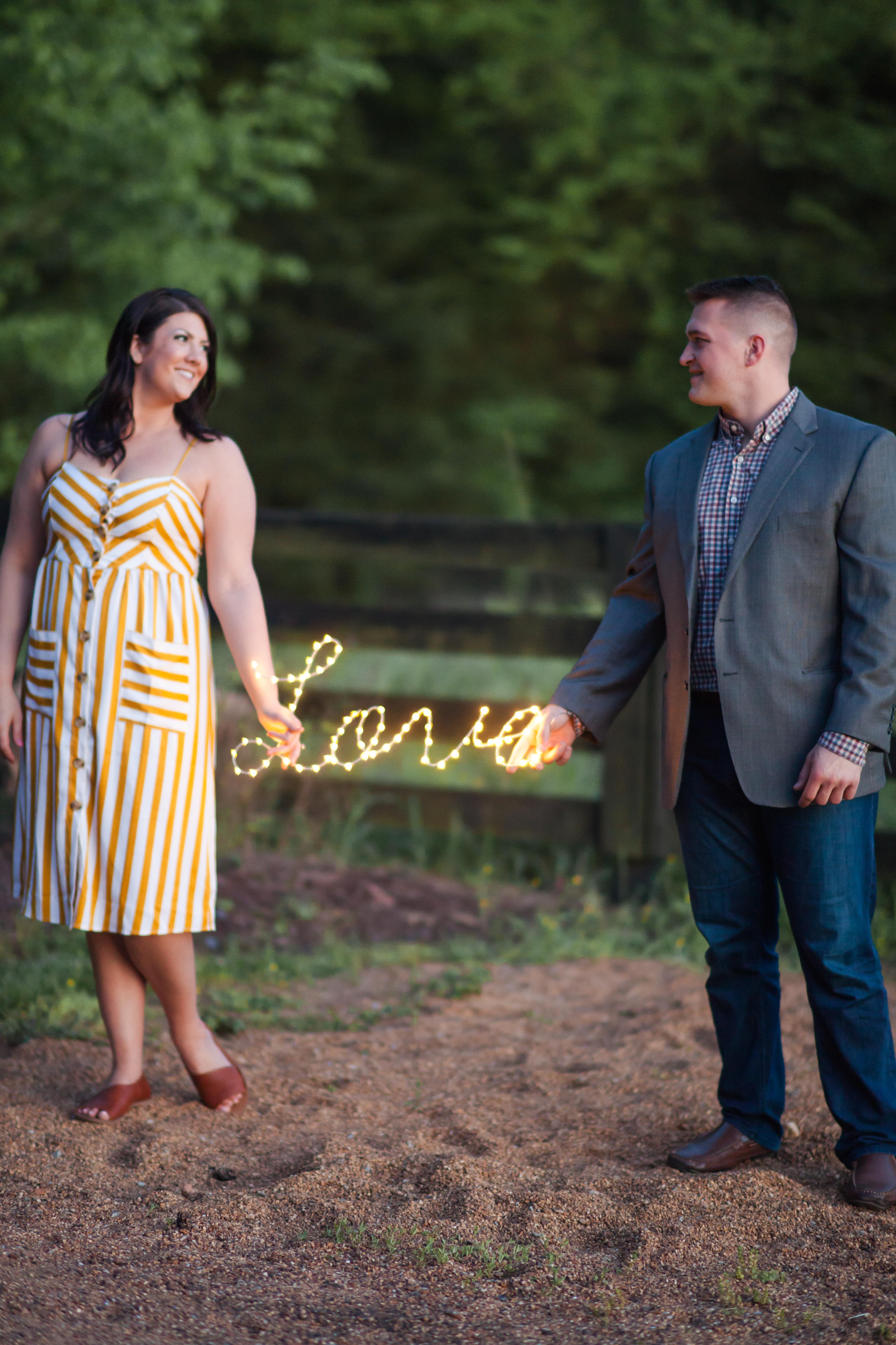 cute couple holding love lighted sign