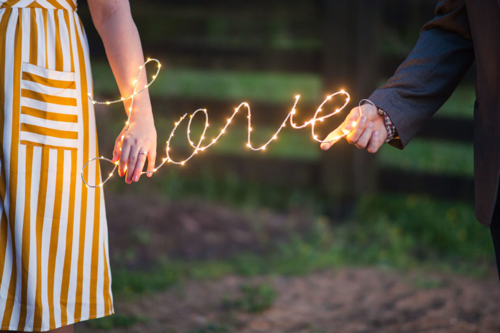couple holding lighted love sign