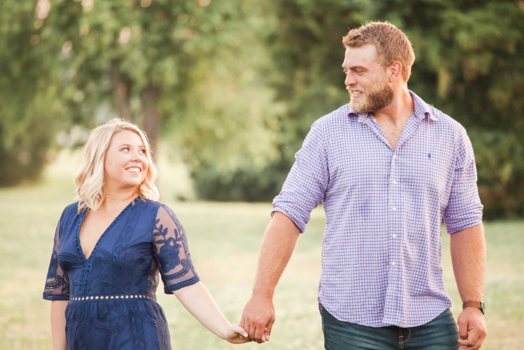 blonde woman in navy lace amazon dress holds hands with guy in jeans and plaid shirt