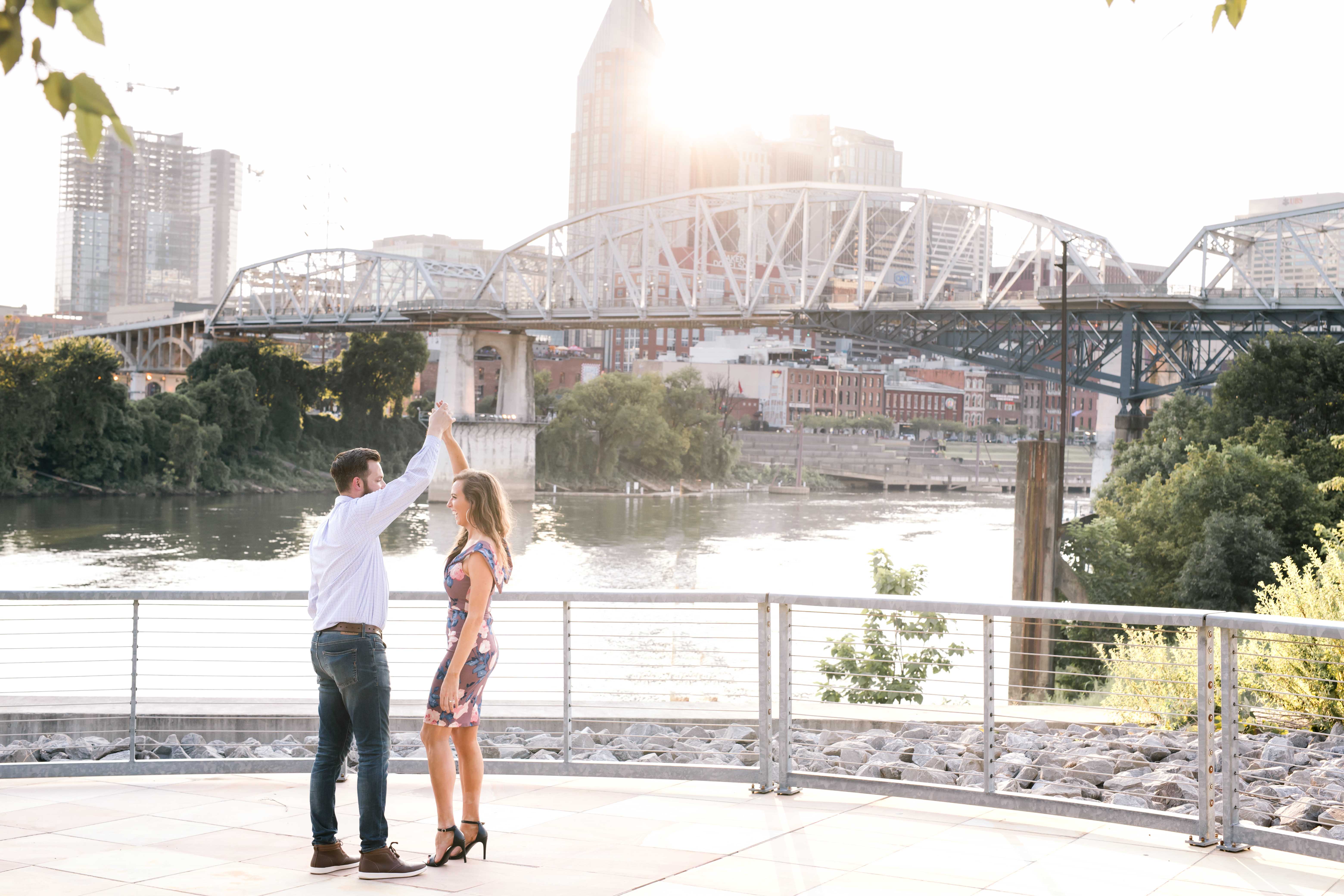 girl in purple dress dancing with guy in jeans in front of nashville skyline