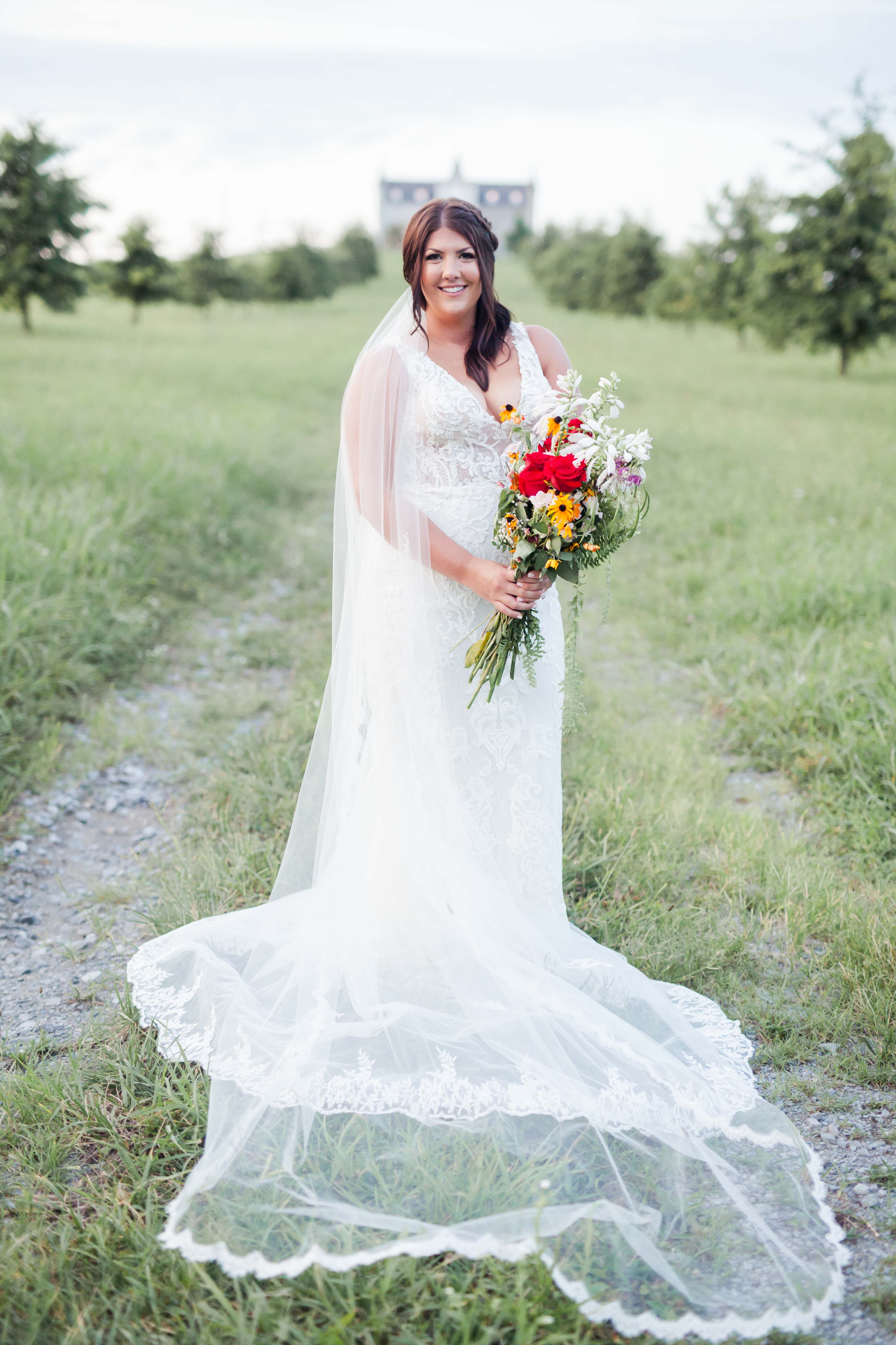 beautiful brown haired bride holding bouquet in front of castle