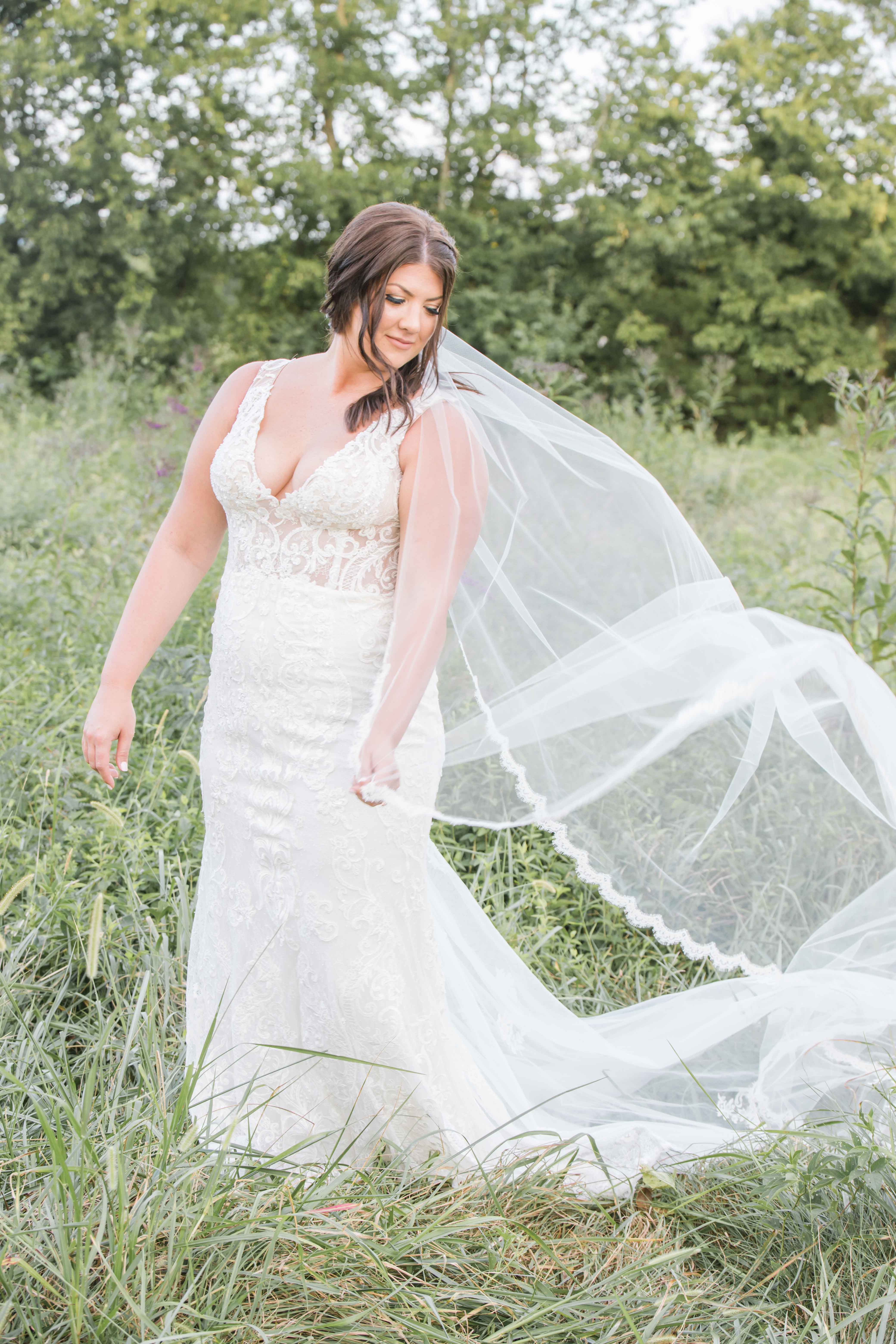 brunette bride in lace gown in field