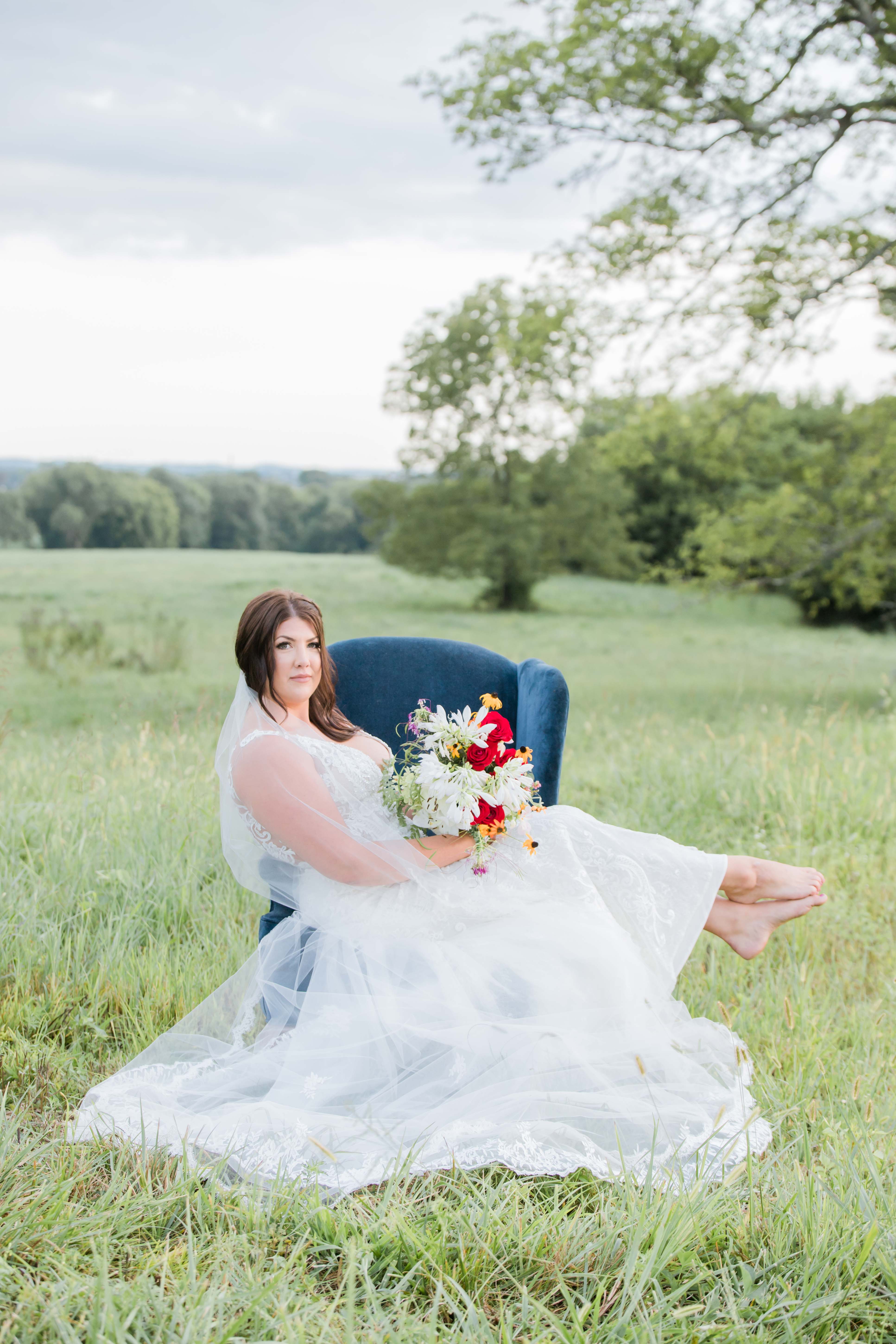 bride sitting in chair in field crossing legs