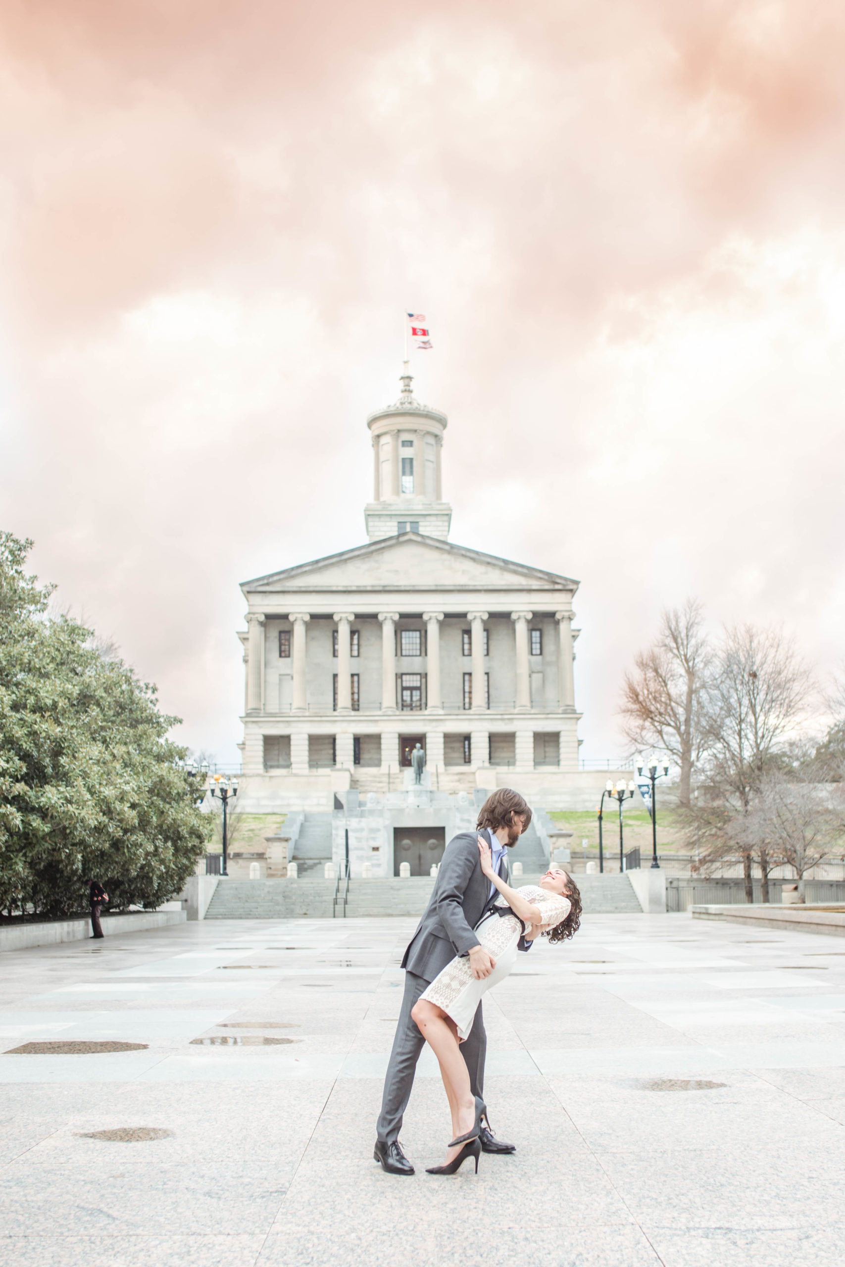 bride in white dress and groom in blue suit in front of tennessee state capital building