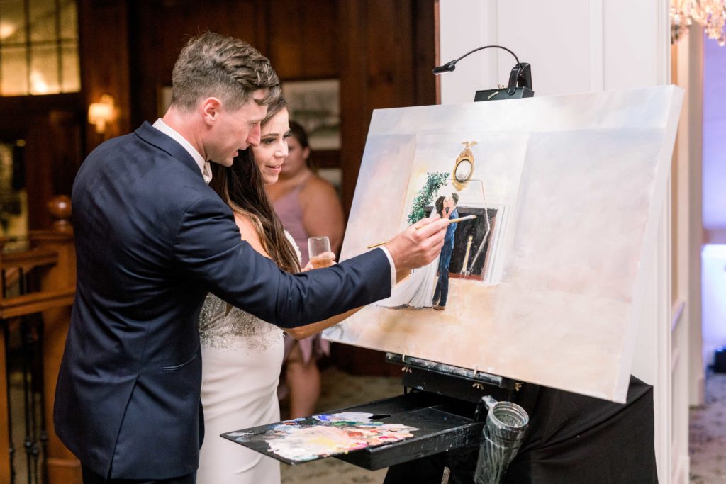 groom in navy tux and bride paint on their custom wedding painting together