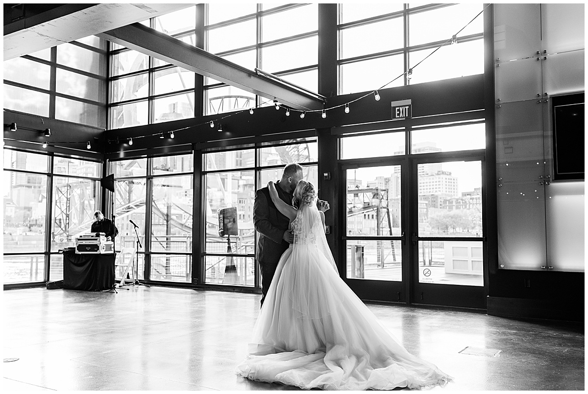 blonde bride in white gown and groom in suit jacket kissing black and white photo of first dance