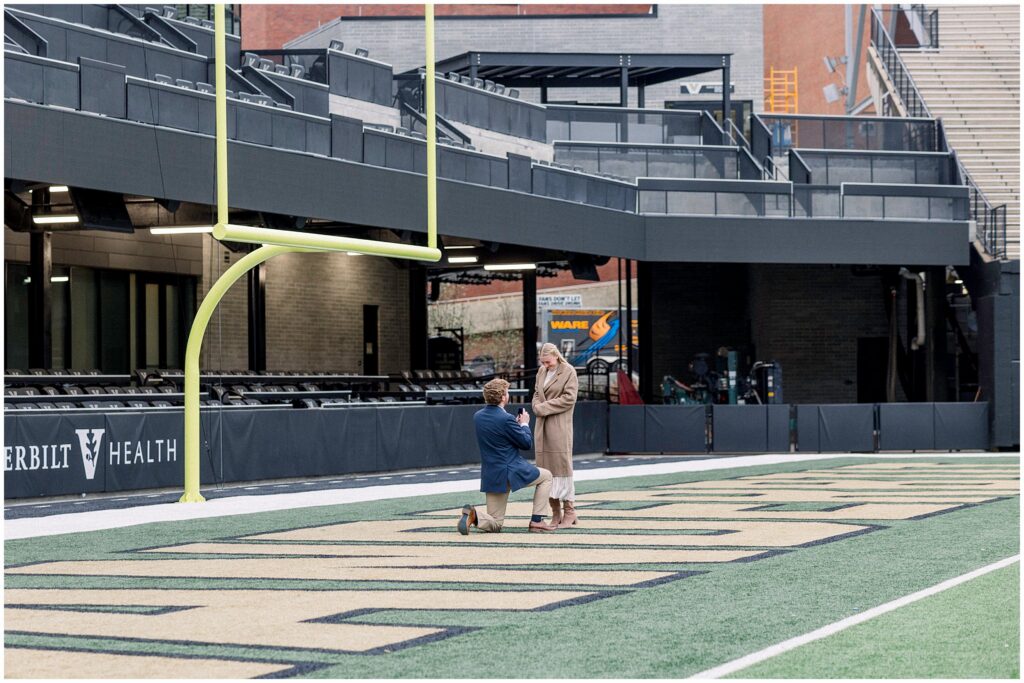guy on one knee proposing in vanderbilt football stadium end zone